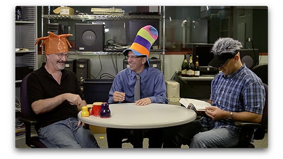 A group of three men seated at a table, participating in a discussion and collaborating on various topics.